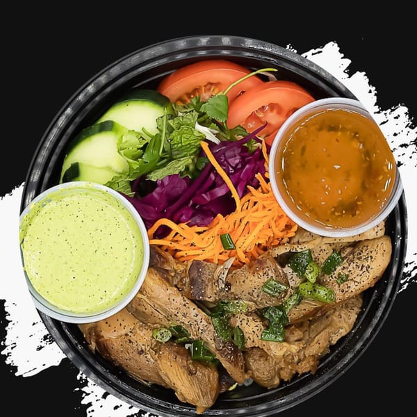 Pho Go's grilled chicken bowl with fresh vegetables and two dipping sauces.