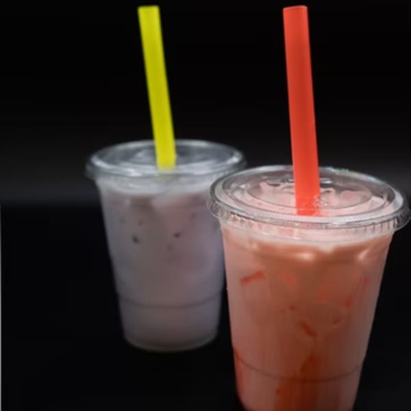 Two bubble tea drinks, one purple with a yellow straw and one pink with a red straw.